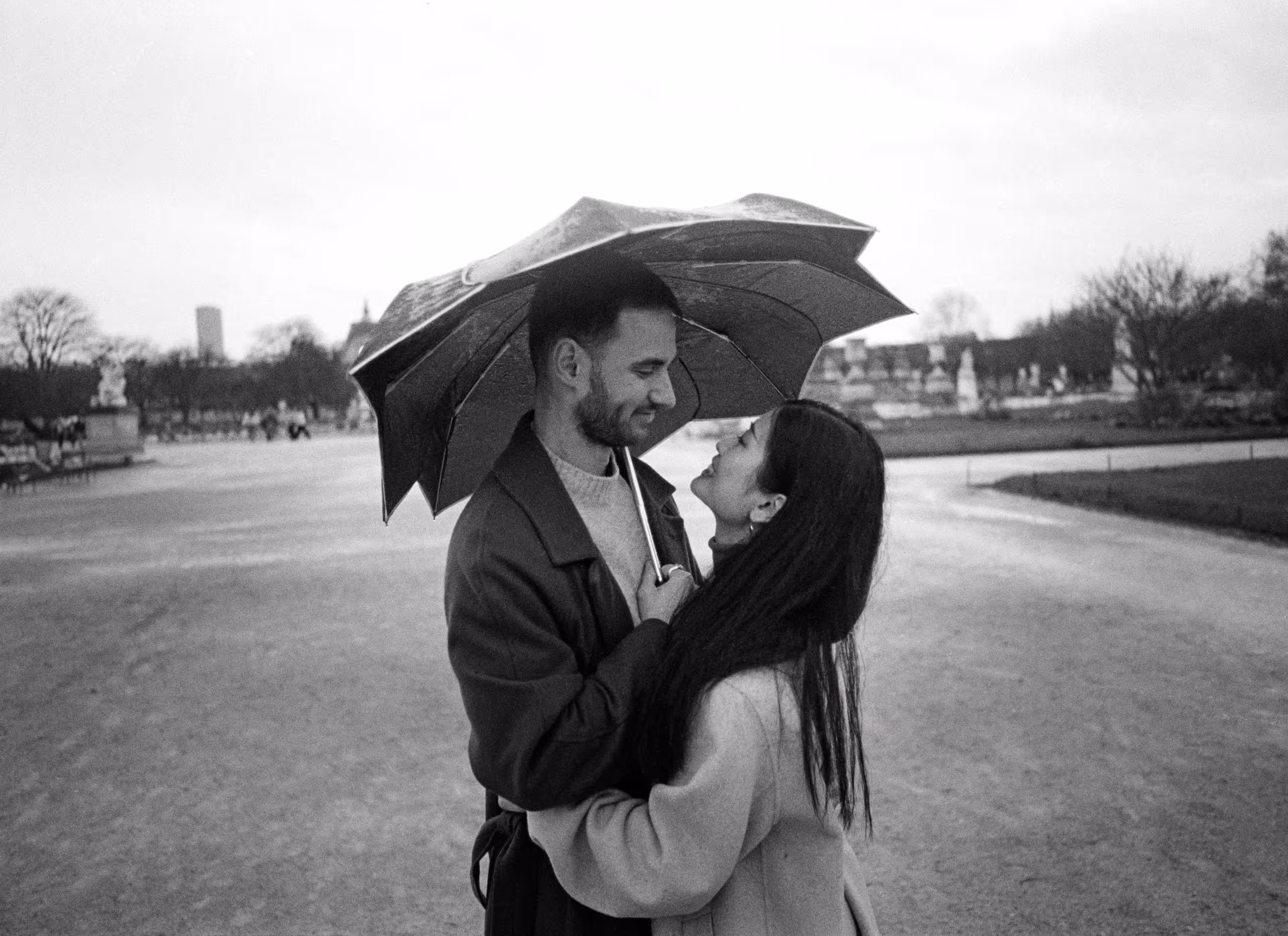 Couple sheltering under an umbrella in the rain in the Jardin des Tuileries