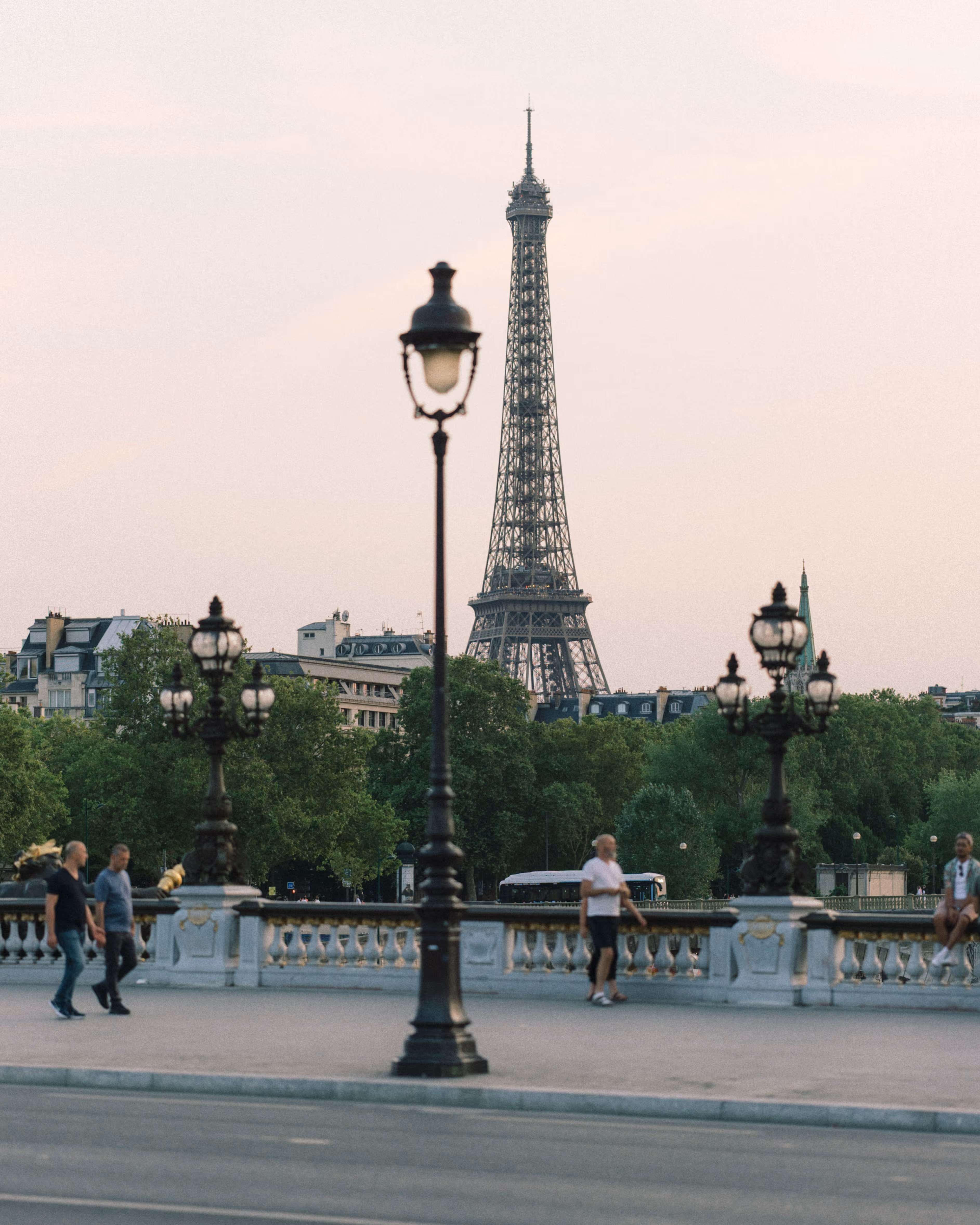 Eiffel Tower seen from Pont Alexandre III, with ornate lamps in the foreground.