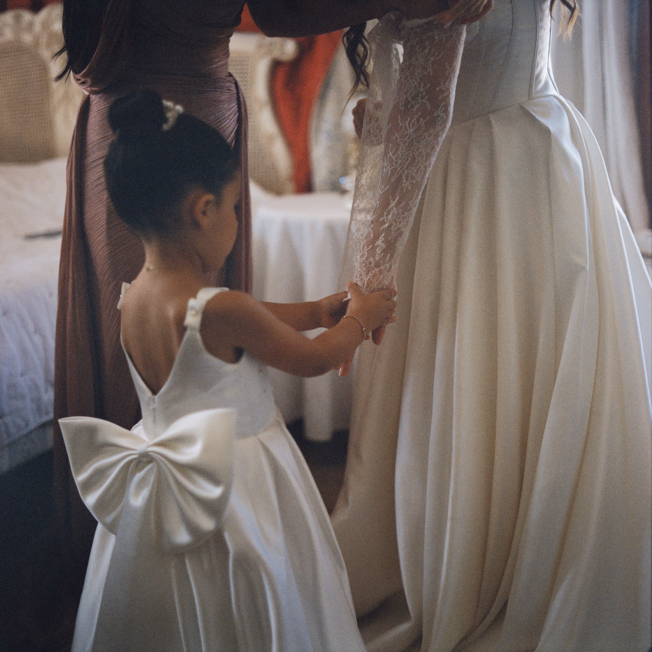 Flower girl in a dress reaching up to the bride, wedding photography, medium format, film photography, south of france, provence, bastide d'astres
