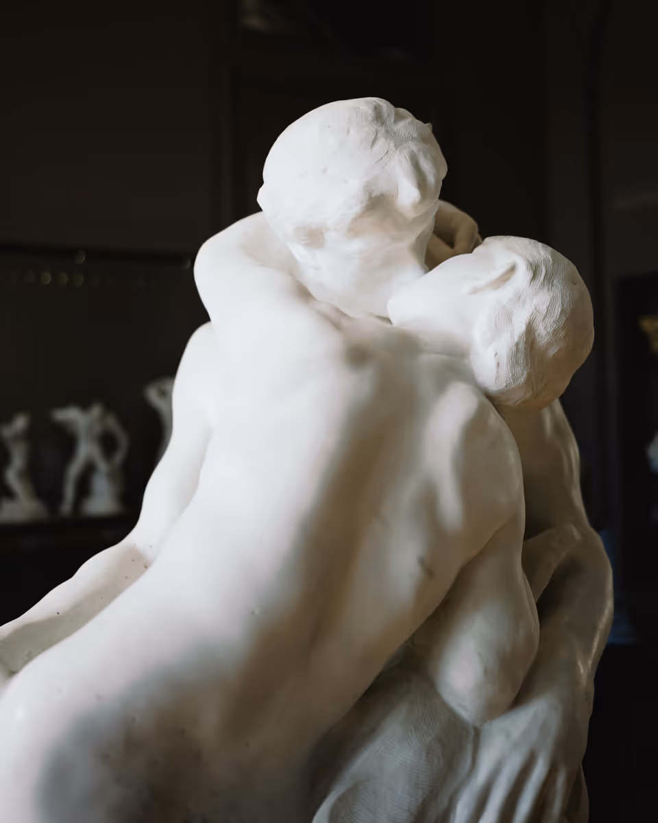 Close view of a white marble sculpture of two figures embracing inside the Musée Rodin.