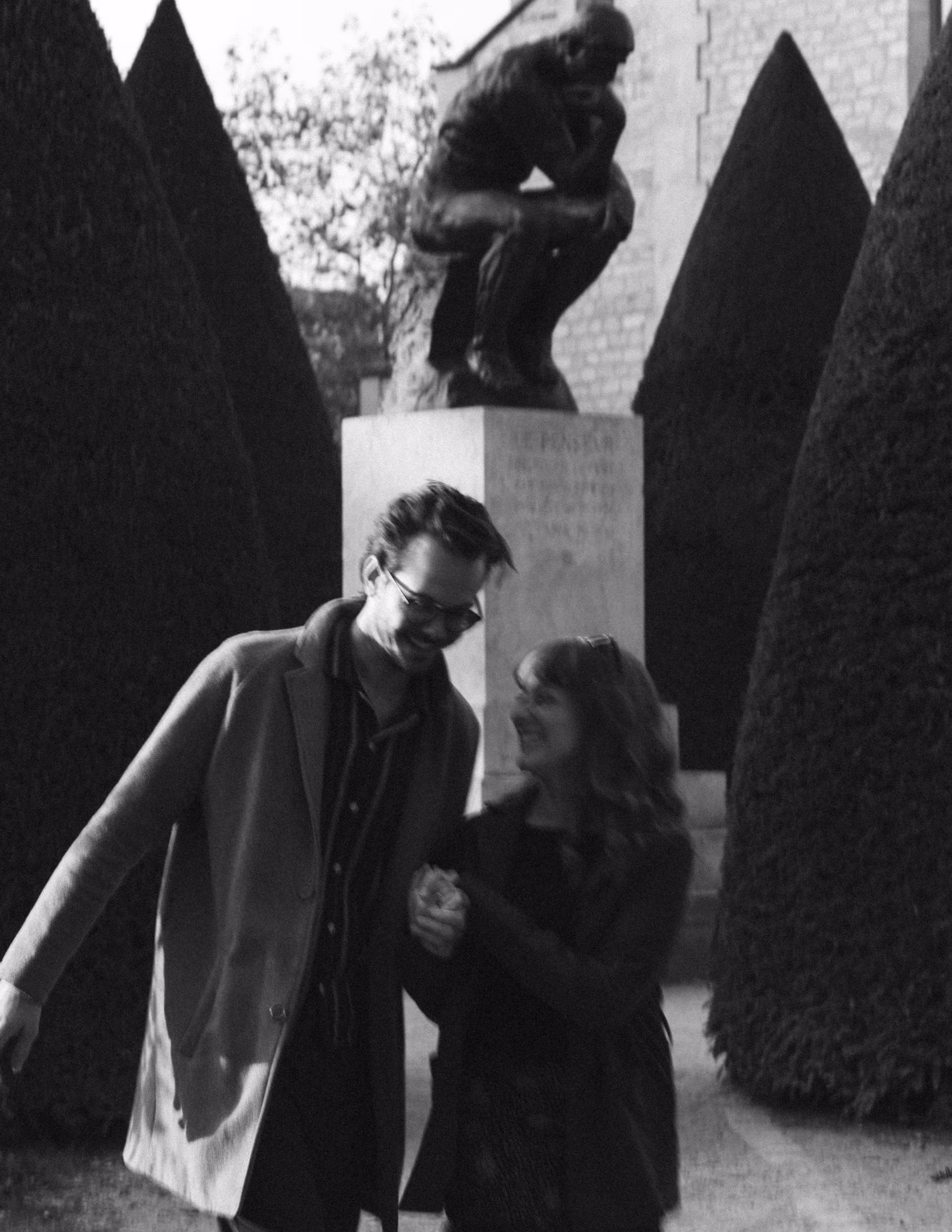Black-and-white photograph of Paige and Reinhardt walking arm in arm between clipped hedges in the Musée Rodin garden.