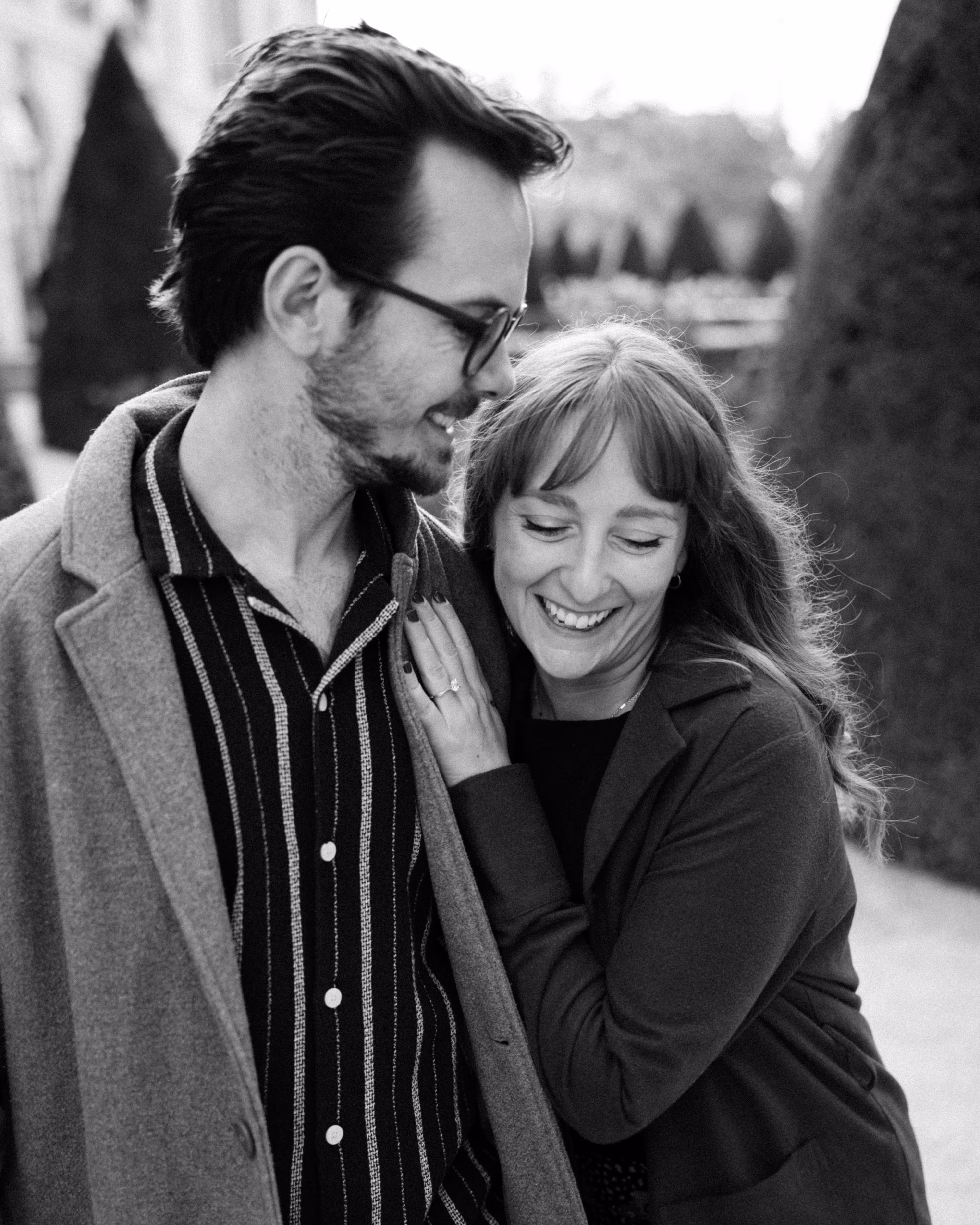 Black-and-white portrait of Paige smiling as Reinhardt leans towards her hair in the Musée Rodin garden in Paris.