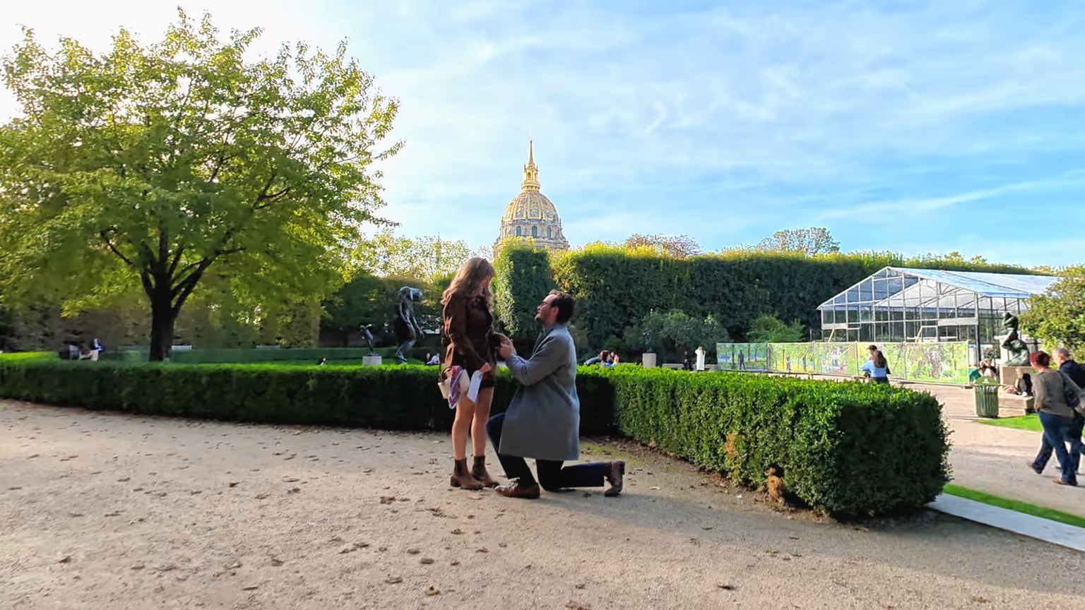 Reinhardt on one knee in front of Paige in the Musée Rodin garden, with the Invalides dome behind them.