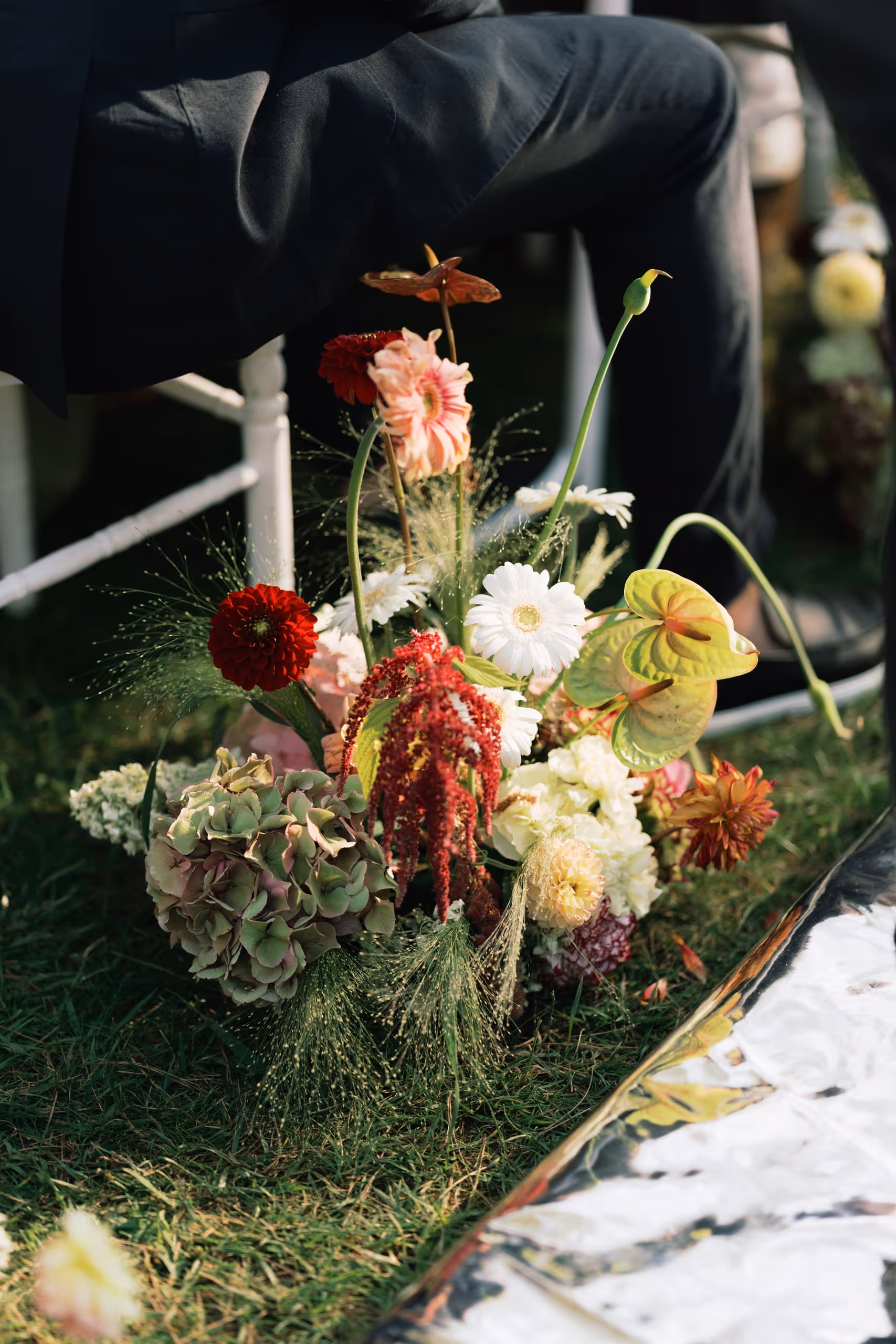 Floral arrangement of dahlias and anthuriums set on the grass by the ceremony aisle, south of france, provence wedding