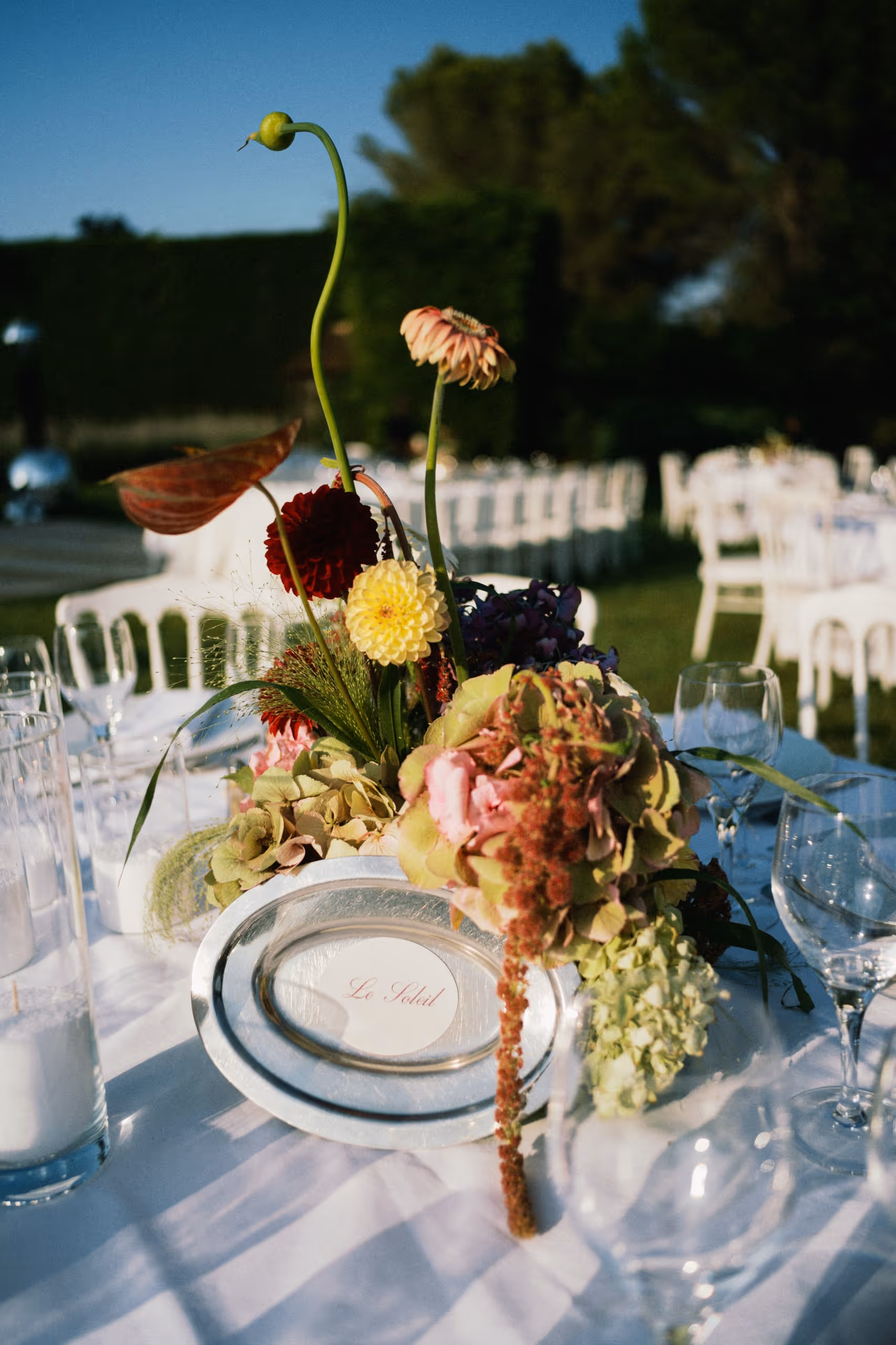 Reception place setting with a low arrangement of garden flowers, laid outdoors, south of france wedding, provence